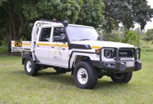 A white FleetCrew mine spec LandCruiser dual cab with tray back, orange reflective tape and mine bar