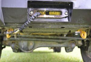 Winch installed behind a bull bar with the cable attached to yellow recovery points beneath the vehicle
