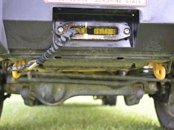 Winch installed behind a bull bar with the cable attached to yellow recovery points beneath the vehicle