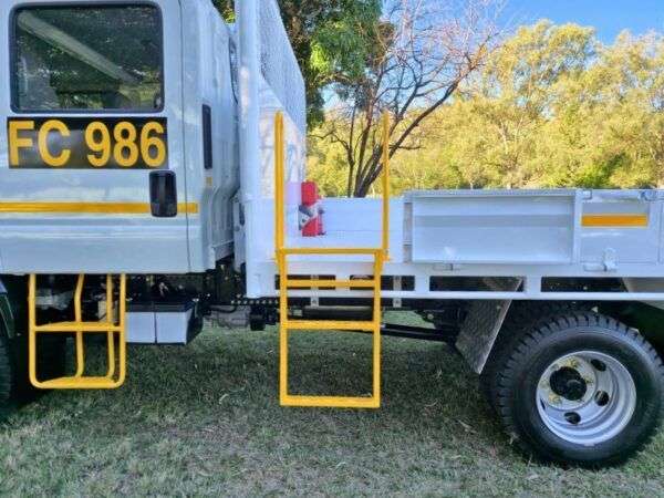 Yellow step ladder attached to the white tray of an Isuzu tray back truck