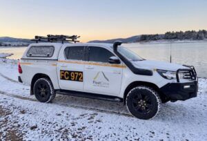 FleetCrew 4WD Hilux fitted with a lockable canopy and ski racks parked next to a lake in the snow